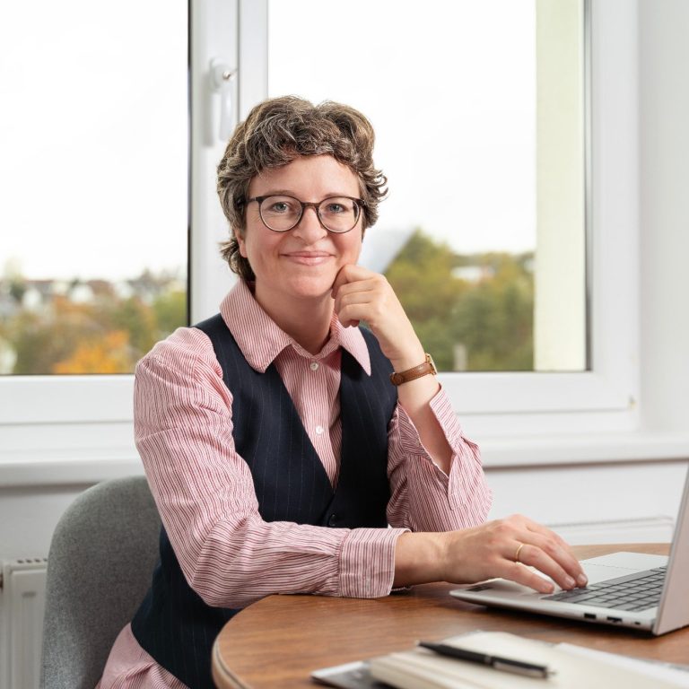 Anne Breitenberger Anne Breitenberger, am Laptop sitzend, schaut in die Kamera